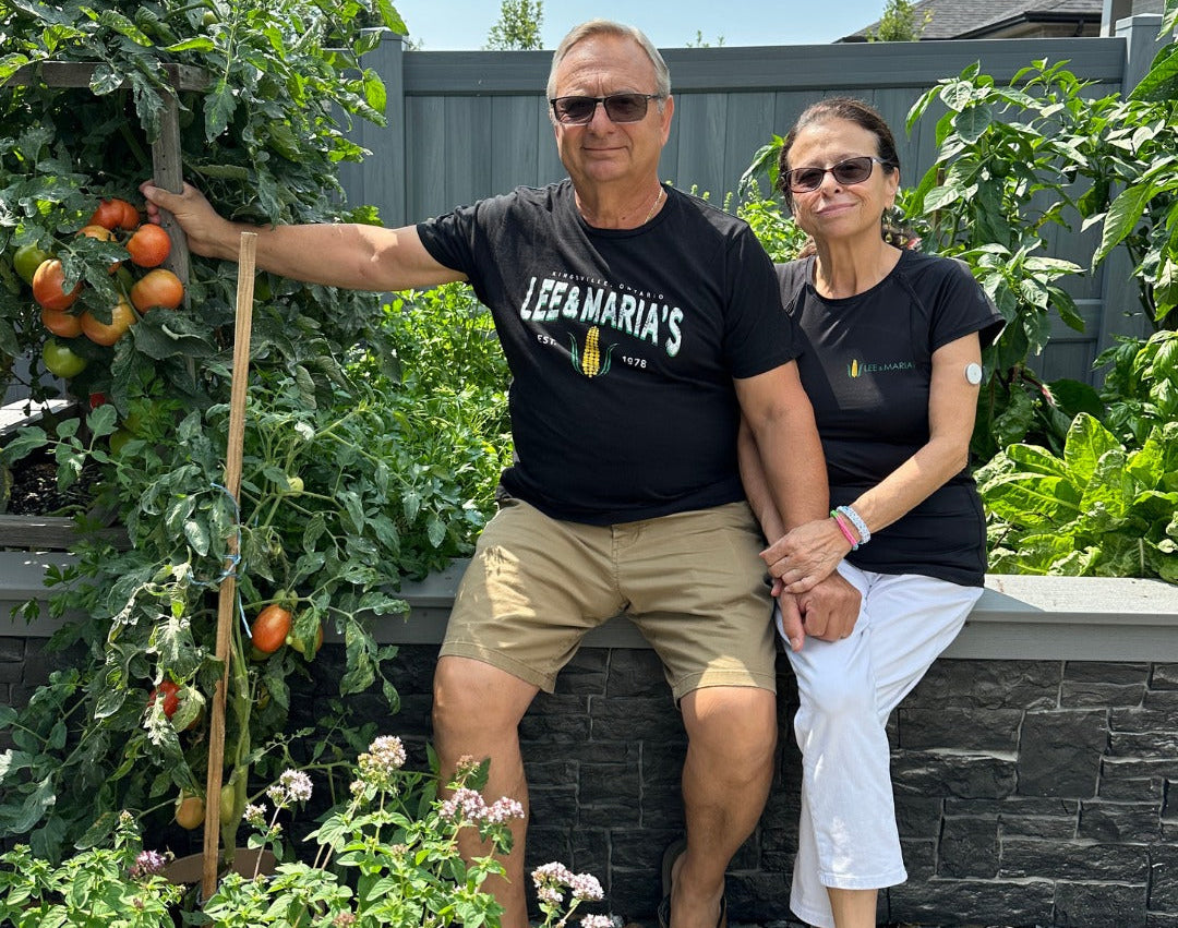 Lee and Maria sitting in their Kingsville garden surrounded by tomatoes and herbs.