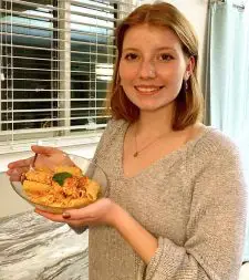 Ava holding a dish of feta pasta