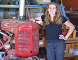 Girl stands beside Farmall Super A tractor